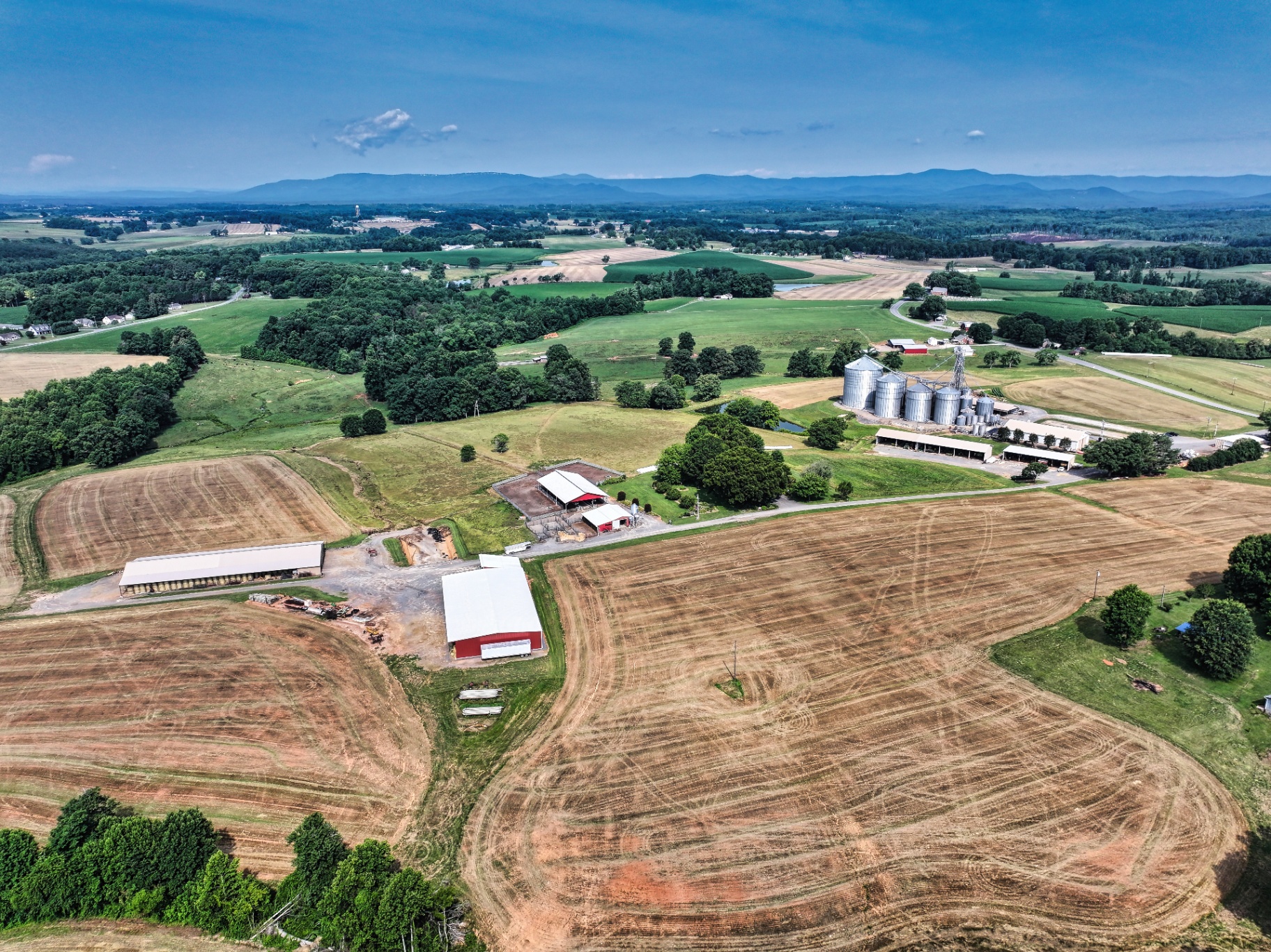Aerial view of farm with grain silos, barns, and Blue Ridge mountains