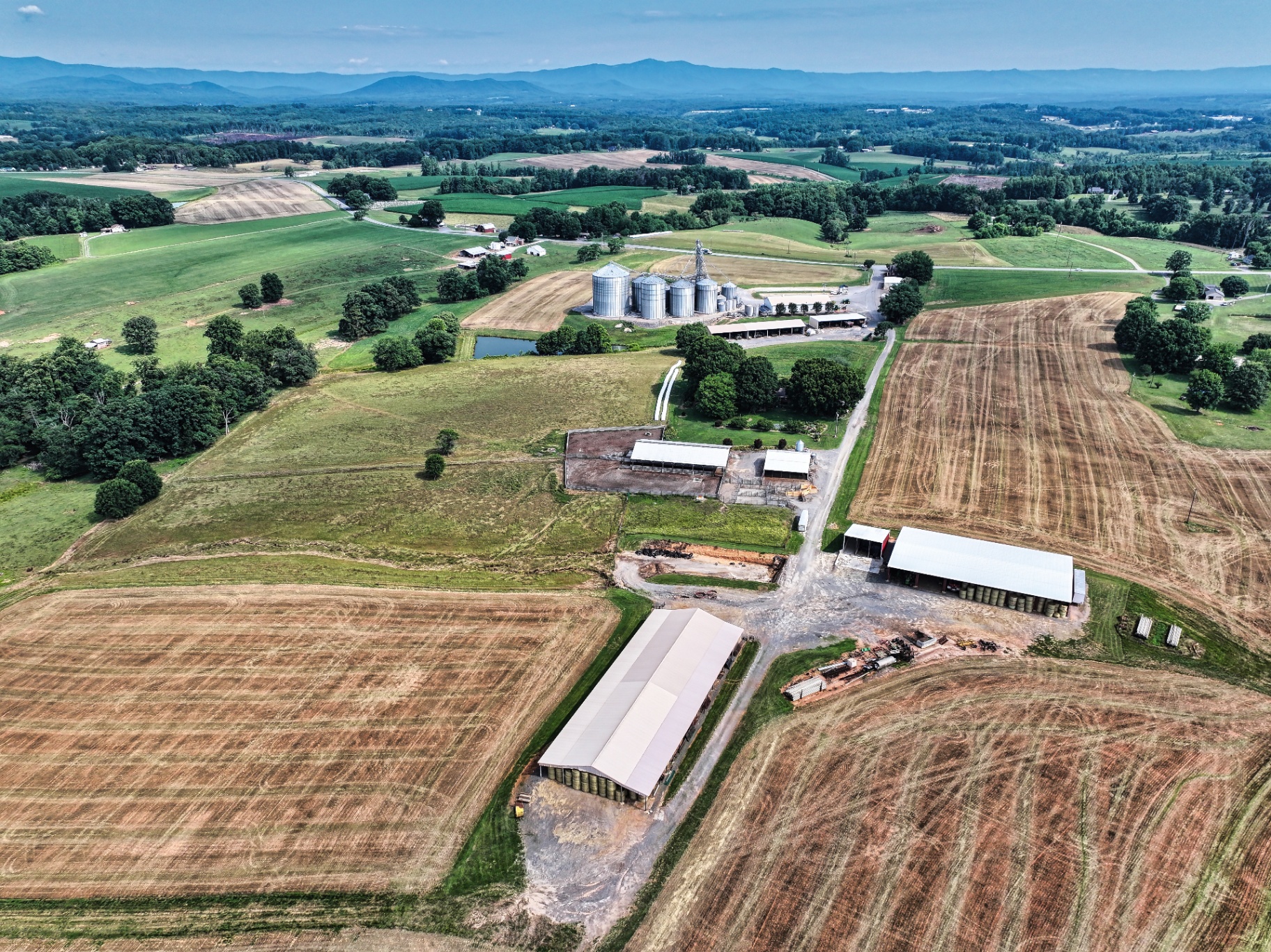 Aerial of grain silos and farm operation with mountain backdrop