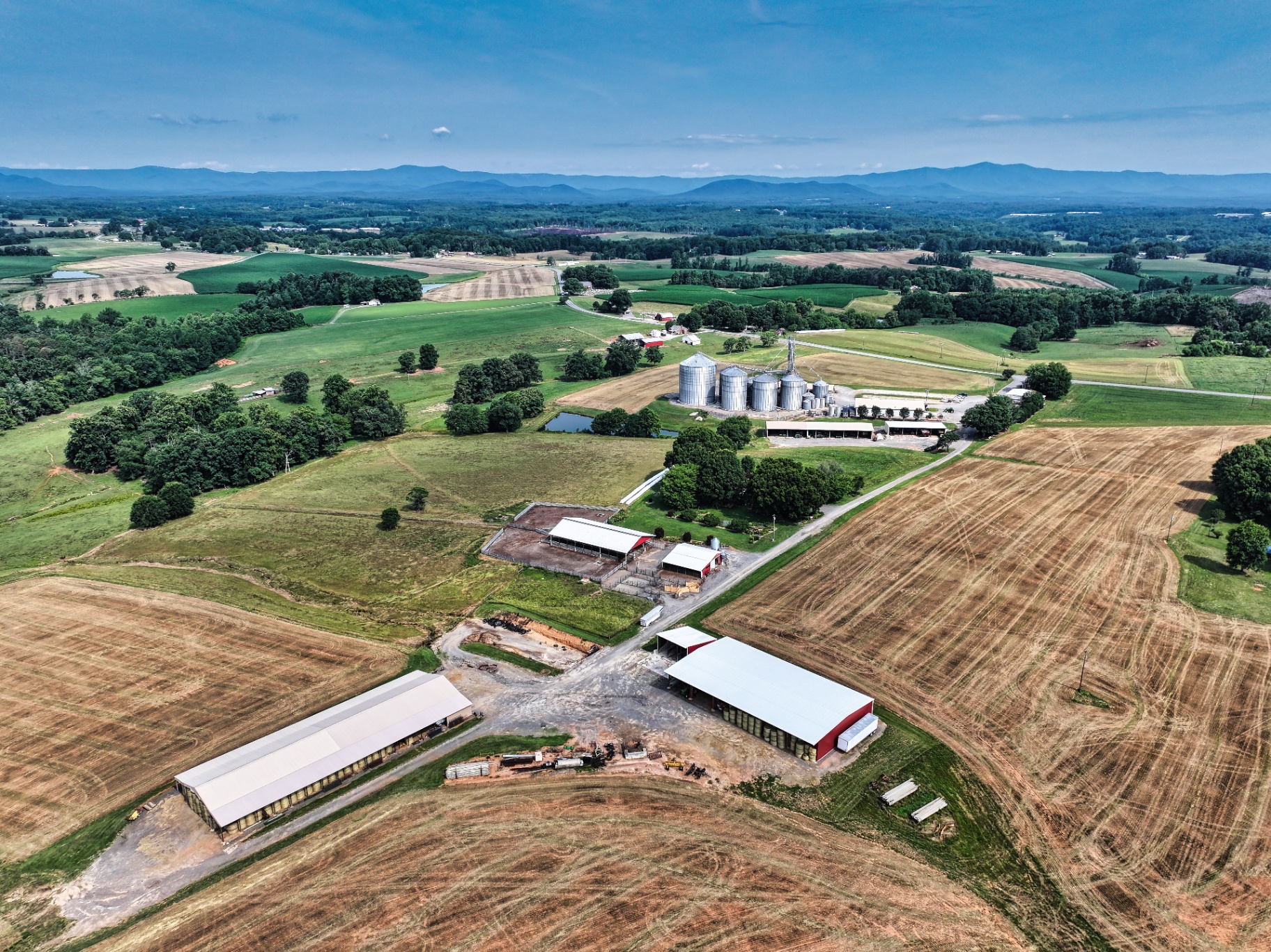 Aerial of farm complex with hay barns and rolling fields